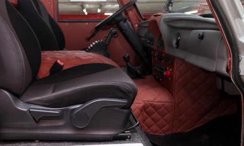 A truck's front passenger door is open, revealing black seats and a red leather cover on the center console.